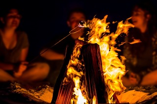 Eine Freundesgruppe grillt Marshmallows über dem Lagerfeuer in West Kanada